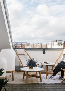 Modern balcony with urban view, minimalist decor, and cosy seating.