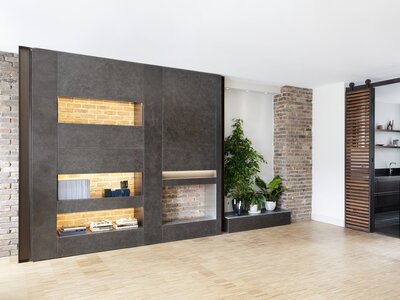 Modern living room with concrete wall, exposed brick, and potted plants.