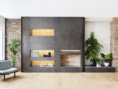 Modern minimalist living room with an industrial and natural aesthetic featuring a concrete wall unit.