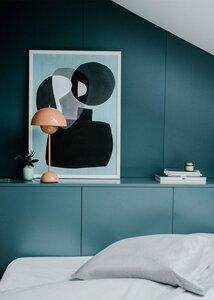 Minimalist attic bedroom with teal wall, abstract art, modern decor, and white bedding.