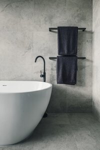 Modern and minimalist bathroom with freestanding bathtub and black matte faucet.