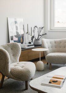 Modern cozy living room with tufted armchairs and light wood accents.