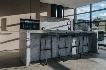 Modern minimalist kitchen with stone island and black stools by CHT Architects.
