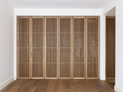 Spacious minimalist room with a large wooden closet and light wooden flooring.
