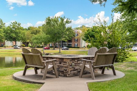 A cozy fire pit with surrounding Adirondack chairs sits in a scenic park area, offering a peaceful spot for residents to unwind and enjoy nature.