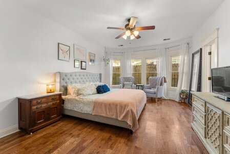 Bright bedroom featuring a tufted headboard, large windows, and mixed vintage-modern furniture.