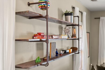 Disco ball decor on industrial-style wall shelf with books and plants.