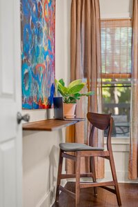 Bright home workspace with wooden chair, desk, and large window with curtains.