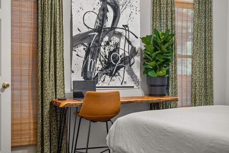 Clever, contemporary workspace featuring a wooden desk, laptop, and bold abstract art.