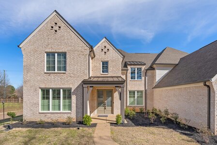 Beautiful brick house exterior with landscaped yard and large windows.