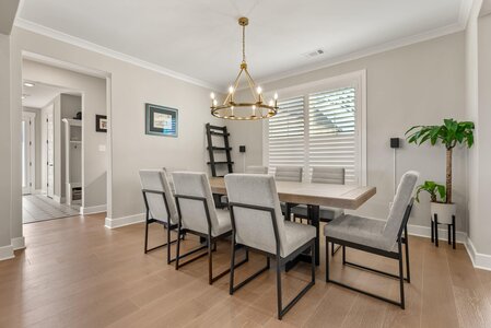 Spacious dining area with contemporary style, featuring a wooden table, light furnishings, and lush greenery.