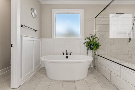 Luxurious bathroom with freestanding tub and walk-in shower. Elegant, modern design with natural light.
