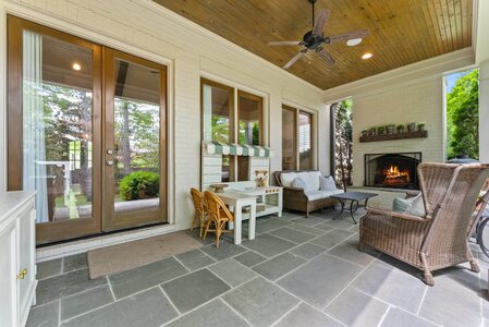 Bright outdoor living space with fireplace, wicker chairs, and scenic views, perfect for gatherings.