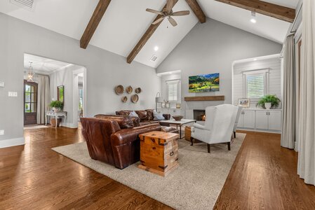 Escape to a stylish living space featuring a vaulted ceiling, fireplace, and rustic wooden beams.