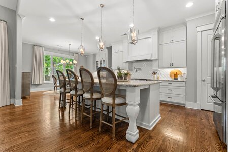Bright white kitchen design featuring island, pendant lighting, and hardwood flooring for stylish home living.