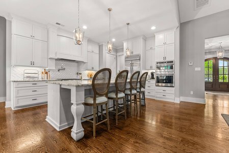 Bright, spacious kitchen with white cabinets and hardwood flooring, perfect for family gatherings.