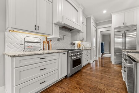 Bright modern kitchen with crisp white cabinets, granite countertops, and stainless steel appliances.