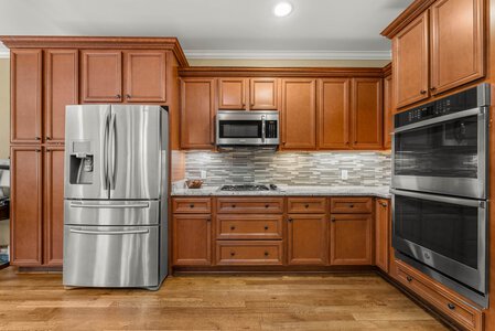 Elegant kitchen featuring warm wood cabinetry and premium stainless steel refrigerator, microwave, and oven.