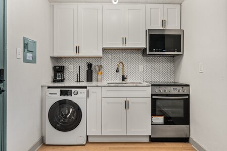 Bright, sleek kitchen featuring white cabinetry, gold hardware, and modern appliances.