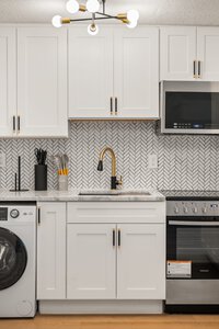 Stylish kitchen interior with white cabinets, gold fixtures, and modern appliances for contemporary home design.