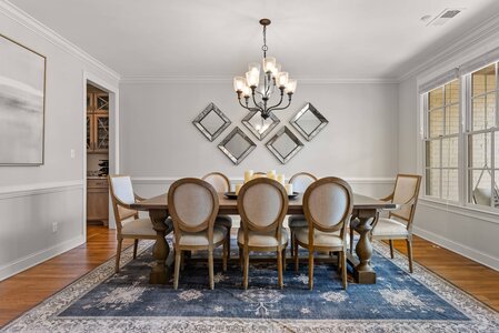 Spacious dining area featuring a wooden table, comfortable upholstered chairs, and contemporary wall mirrors.