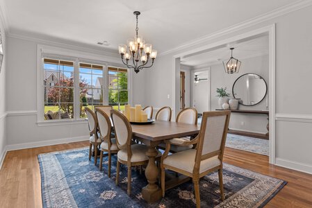 Bright dining space featuring large window, wooden table, and traditional chandelier, ideal for family gatherings.