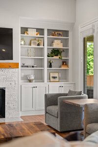 Bright living room with white shelves, decorative items, and a gray armchair for relaxation.