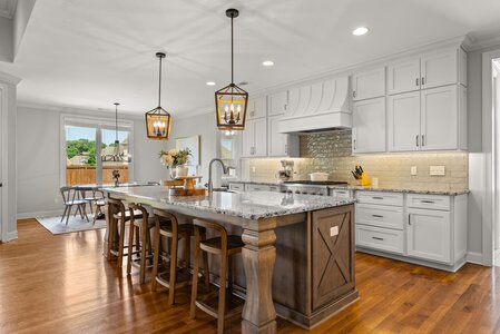 Bright, spacious kitchen featuring white cabinetry, granite countertops, and pendant lighting.