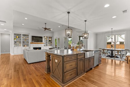 Bright spacious kitchen with island, living room, and elegant pendant lighting.