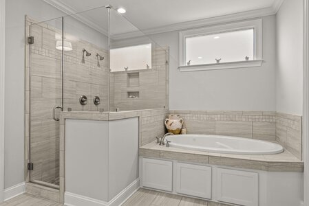 Luxurious bathroom featuring a spacious walk-in shower, bathtub, and contemporary design with natural light.