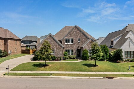Beautiful suburban brick home featuring lush landscaping and a spacious front yard.