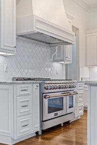Stainless steel professional range in modern white kitchen.