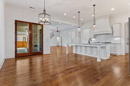 Bright spacious kitchen with white cabinetry, marble countertops, and large glass doors for outdoor access.