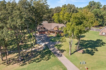 Aerial view of a charming house nestled among tall trees and lush greenery.