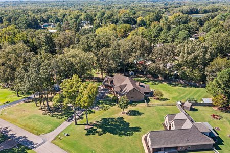 Aerial view of a large house in a lush, tree-lined neighborhood with expansive yard space, ideal for family living and outdoor activities.