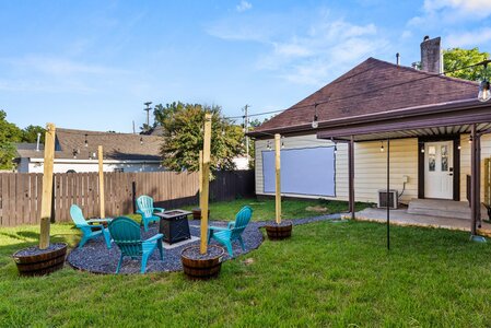 Backyard party area with Adirondack chairs, string lights, and outdoor privacy fence.