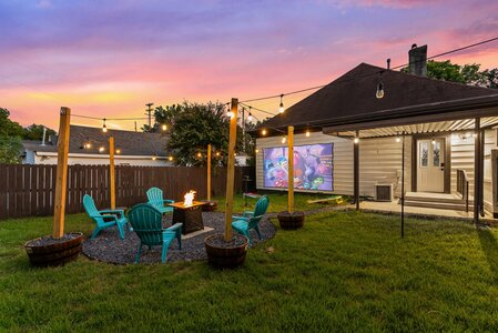 High-quality image of backyard entertainment setup with string lights, outdoor seating, and projector at dusk.