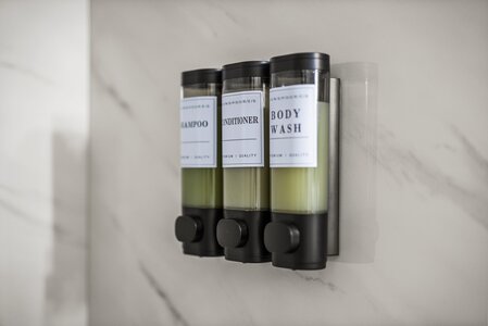 Bathroom soap dispenser holding shampoo, conditioner, and body wash bottles for organized bathroom décor.
