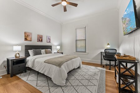 Bright bedroom featuring a large bed, minimalist furniture, and natural light for relaxed living.