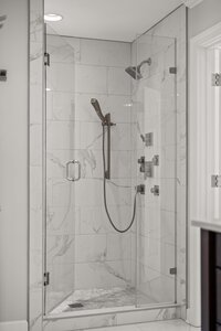A sleek bathroom shower with glass doors, marble tiles, and contemporary fixtures promoting luxury and relaxation.
