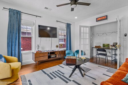 Bright living space featuring colorful furniture, large windows, and a dedicated recording studio nook for music and video projects.