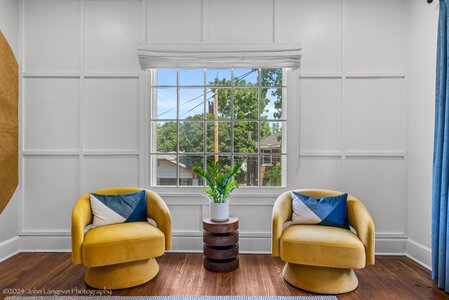 Stylish living room with bright yellow chairs, decorative pillows, and a lush plant by the window.