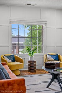 Bright living room with large window, yellow and orange armchairs, and modern interior design.