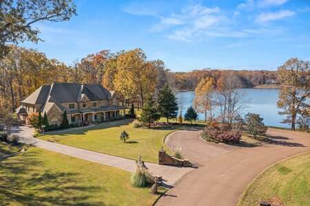 Beautiful lakeside house surrounded by colorful fall trees, showcasing luxury living and serene natural scenery.