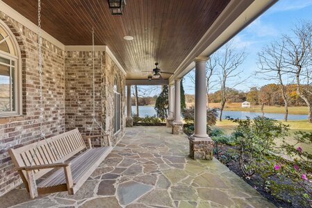 Scenic porch with swing, columns, and lake view, perfect for outdoor relaxation.