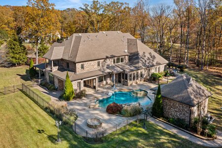 Aerial view of a spacious house with a private pool and landscaped yard in fall focusing on luxury real estate.