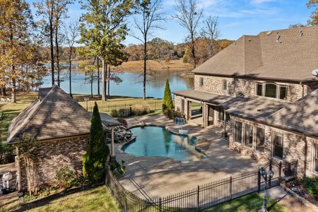Aerial view of a luxury residential property featuring a swimming pool and lakefront scenery.