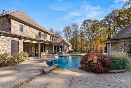Beautiful backyard with swimming pool, stone accents, and surrounding trees.