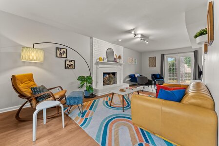 Bright, stylish, inviting living room with colorful furniture, cozy fireplace, and natural light.