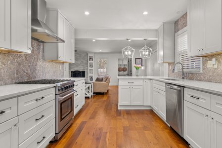 Bright, modern kitchen with white cabinetry, stainless steel appliances, and warm wooden flooring.
